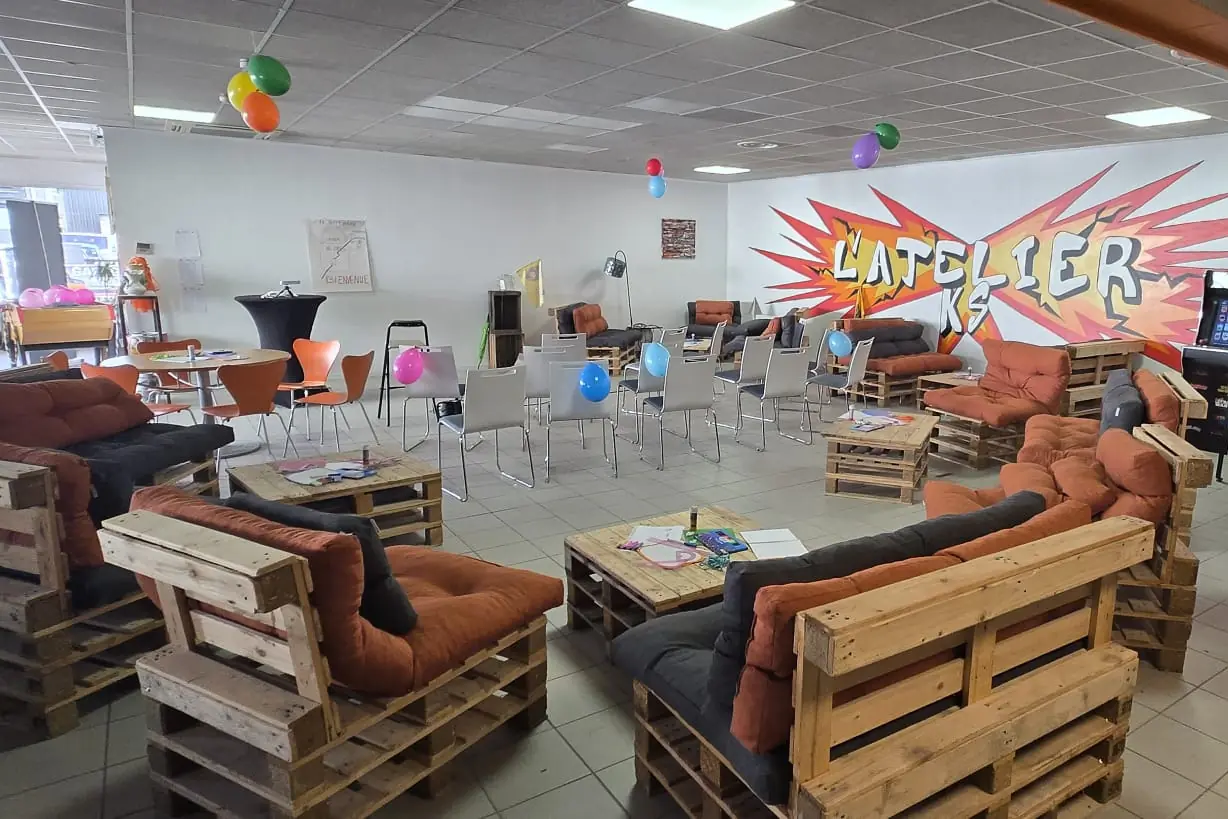 Le lounge de l'AtelierKS à La Rochelle décoré de ballons : canapés en palettes, tables basses couvertes de feuilles et de feutres, rangées de chaises devant le graff de l'atelier