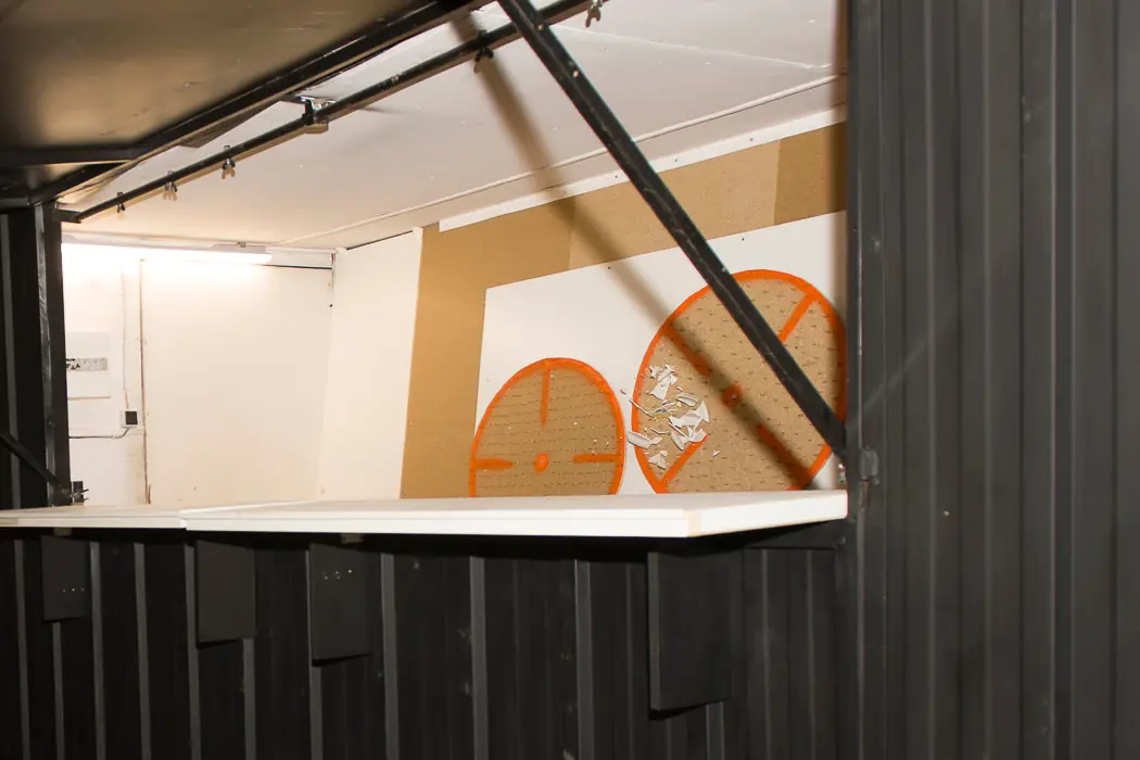 De nuit, le poste de lancer de la Kastou Mobile : le comptoir et les cibles orange, des éclats d'assiette sur l'une d'elles.