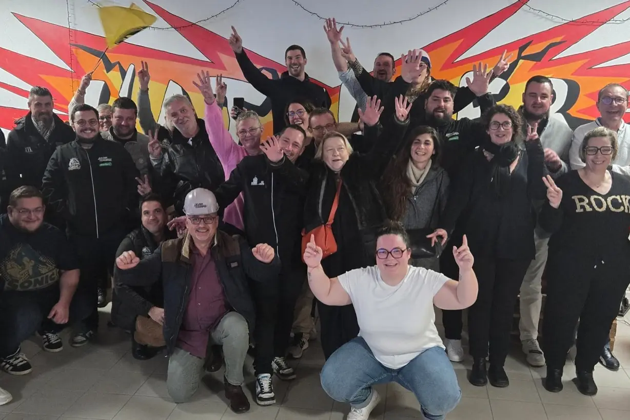 Un groupe de 35 personnes, bras levés, devant la fresque de L'Atelier KS après sa séance de team building.