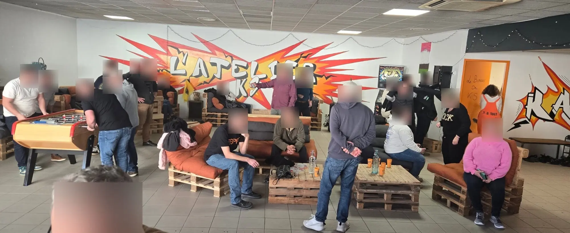 Le lounge de l'AtelierKS pendant un team building : le groupe attend son passage en rage room, au baby-foot et sur les canapés en palettes